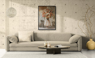 Black-framed flower market art print hanging above a wide beige sofa in a concrete-walled living room