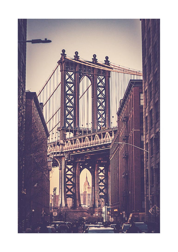Vintage-style photo of the Brooklyn Bridge framed by city buildings, with the Empire State Building visible in the distance.