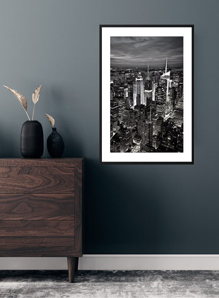 Framed City of New York poster featuring a black-and-white cityscape hanging above a wooden cabinet.