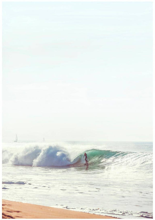 A surfer riding a wave close to the shore under a clear, bright sky.