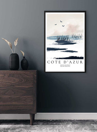 Cote d'Azur Landscape Plakat poster in black frame hanging on a dark gray wall above a wooden dresser.