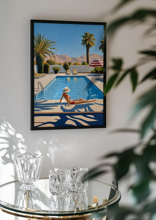 Poolside Afternoon by Elena Avanesova in a black frame above a glass table with crystal glassware