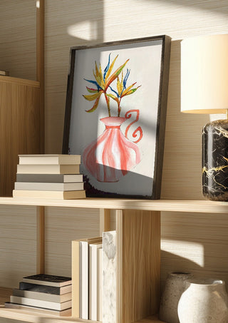 Bird of paradise by Marjorie Salvagni in a dark frame on a wooden shelf beside books and a lamp