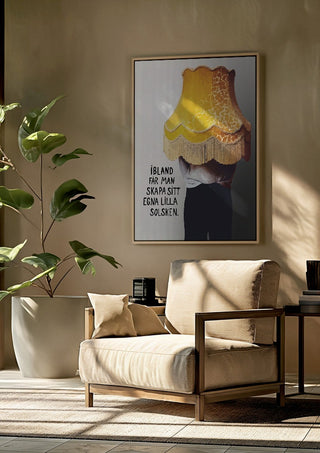 Solsken by Grafik bageri framed above a beige armchair beside a potted plant