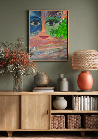 Face Above Pastel Waters by Camilla Sabrina above a wooden sideboard on a sage green wall