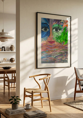 Face Above Pastel Waters by Camilla Sabrina in a black frame in a bright dining room with wooden chairs