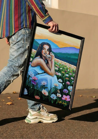 Where Wildflowers Dream by Nella Hajdu carried in a black frame along a sunny street