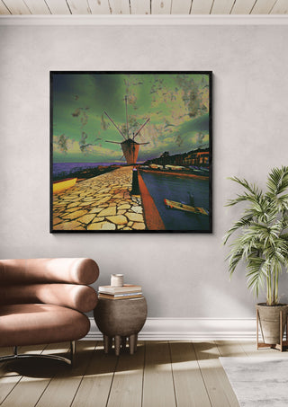 Garitsa Windmill by Pelecan Schneider in a black frame above a tan leather chair beside a potted plant