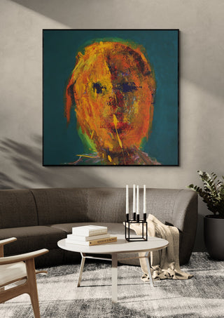 Head in Orange by René J in a black frame above a grey sofa with a round coffee table and candlesticks