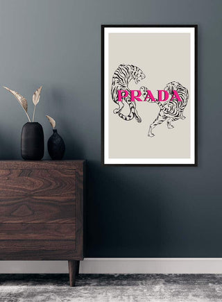 Framed Prada poster with two illustrated tigers and bold pink logo, elegant decor on a modern dresser.