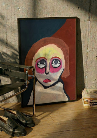 Kreativ by RR in a black frame leaning against a concrete wall by a steel chair