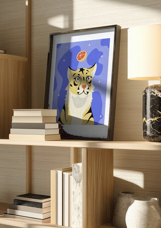 Grrrapefruit by Jakob Falkenberg in a dark frame on a wooden shelf beside books and a lamp