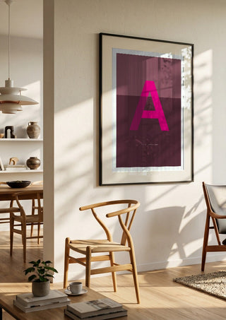 A as in Awesome – Cerise by Quite Nice Prints in a black frame in a bright dining room with wooden chairs