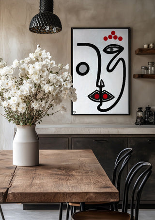 Face by RA in a black frame above a rustic table with white flowers