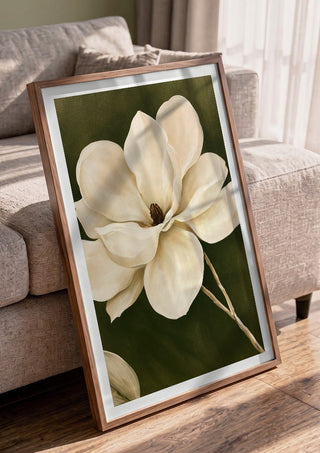 White Magnolia by Martina Karlsson in a walnut frame leaning against a grey sofa