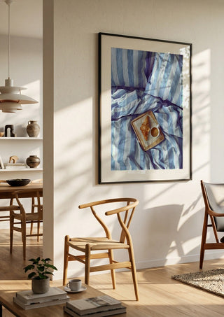 A Cozy Sunday in Bed by Ohkimiko in a black frame in a bright dining room with wooden chairs