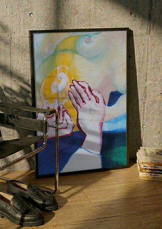 Between the Hands by António D'Albuquerque in a black frame leaning against a concrete wall by a steel chair