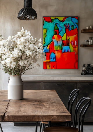 The Village by Nittaart in a black frame above a rustic table with white flowers