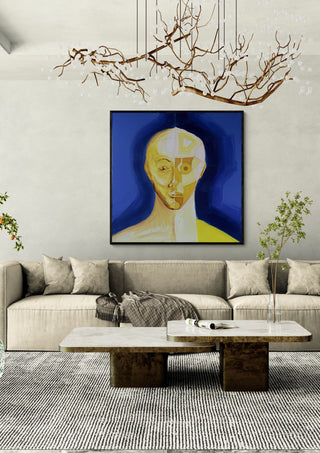 Ochre portrait / blue field by Linor Citaku in a black frame above a cream sofa under a branch chandelier