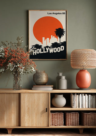 Los Angeles 89 by Bo Lundberg above a wooden sideboard on a sage green wall