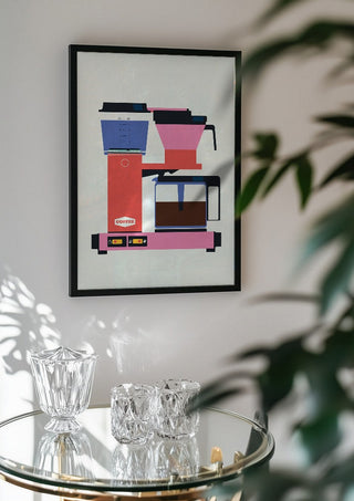 Pastel coffee by Bo Lundberg in a black frame above a glass table with crystal glassware