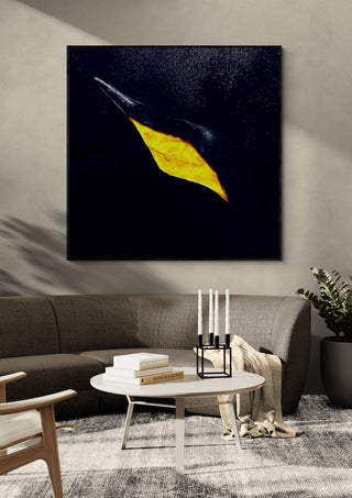 The golden crack by Marcel Herrmann in a black frame above a dark sofa with candlesticks on a round table