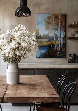 Autumn Birches by the Pond by Lüba in a black frame above a rustic table with white flowers
