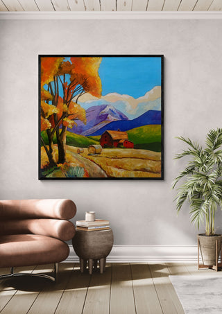 Autumn Fields by Evgenia Smirnova in a black frame above a leather armchair beside a palm