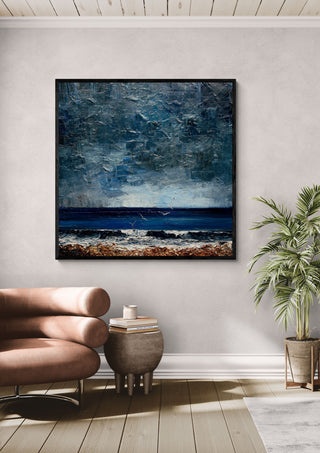 Surf under a Grey Sky by Justyna Kopania in a black frame above a leather armchair beside a palm