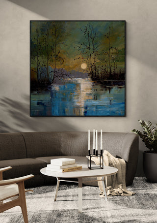 Sun over Still Water by Justyna Kopania in a black frame above a dark sofa with candlesticks on a round table