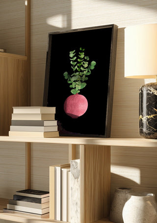 Eucalyptus in pink vase by Creationsbyeditabrus in a dark frame on a wooden shelf beside books and a lamp