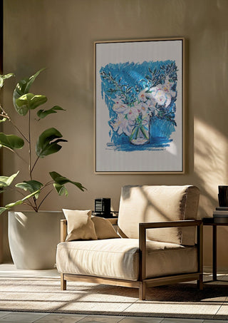 White Blooms on Blue by DNF framed above a beige armchair beside a potted plant