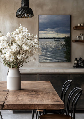 Light Reaching the Water by Bora Kőhalmi in a black frame above a rustic table with white flowers