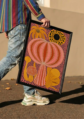 Pink Dotted Pumpkin by Yokohama carried in a black frame along a sunny street