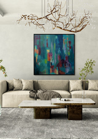 Beginnings by Janet Bell in a black frame above a pale sofa under a branch chandelier