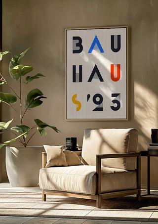 Bauhaus Letters by Neil Stevens framed above a beige armchair beside a potted plant