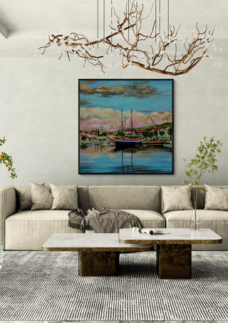 Nice City by Sunny in a black frame above a beige sofa under a branch chandelier
