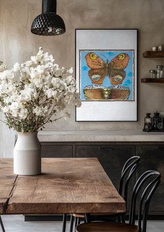 The Butterfly and the Book by Waldemar Mandzel in a black frame above a rustic table with white flowers