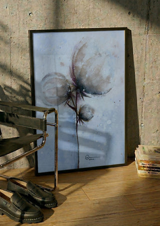 Cotton by Marina Agre in a black frame leaning against a concrete wall by a steel chair