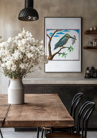 Bird with a Book by Waldemar Mandzel in a black frame above a rustic table with white flowers