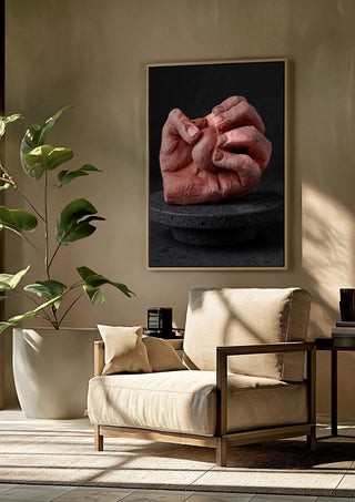 Hold Me - Terracotta Hands by Ammar framed above a beige armchair beside a potted plant