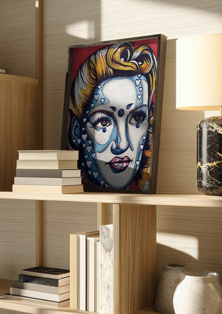 Pinup Girl by Okiana in a dark frame on a wooden shelf beside books and a lamp