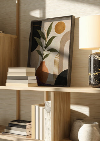 Terracotta Vase with Green Leaves by TimlessArtworks in a dark frame on a wooden shelf beside books and a lamp