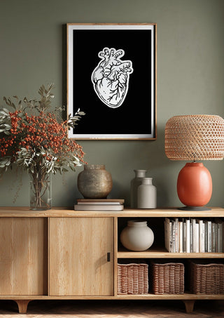 Still Beating by Nari above a wooden sideboard on a sage green wall