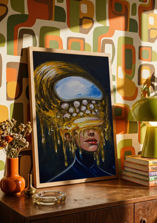 Between Worlds by Ronny Simon in a wooden frame on a sideboard against retro patterned wallpaper