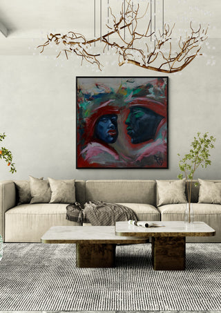 Meeting in Red by Ronny Simon in a black frame above a beige sofa under a branch chandelier