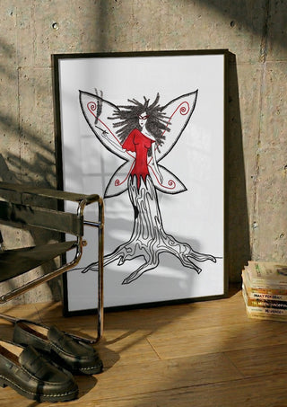 Freedom fairy by A Sleepy Spirit Art in a black frame leaning against a concrete wall by a steel chair