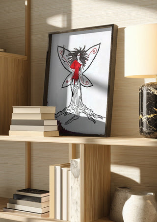 Freedom fairy by A Sleepy Spirit Art in a dark frame on a wooden shelf beside books and a lamp