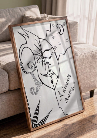 A dreams' reality by A Sleepy Spirit Art in a walnut frame leaning against a grey sofa