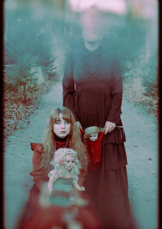 Edge of darkness by Bettinafloorphoto - a woman and a girl in red with dolls on a forest path